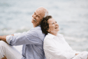 IDEAL Pflegerente: älteres, lachendes Ehepaar Rücken an Rücken